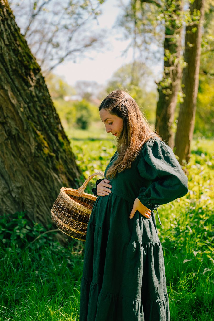 Femme enceinte portant la robe Ampla mater vert forêt profonde, une main sur le ventre