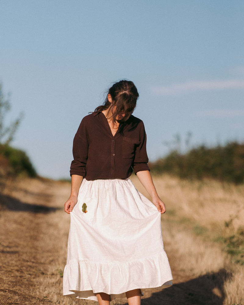Jupe Nativa écru pur, portée avec une chemise brune